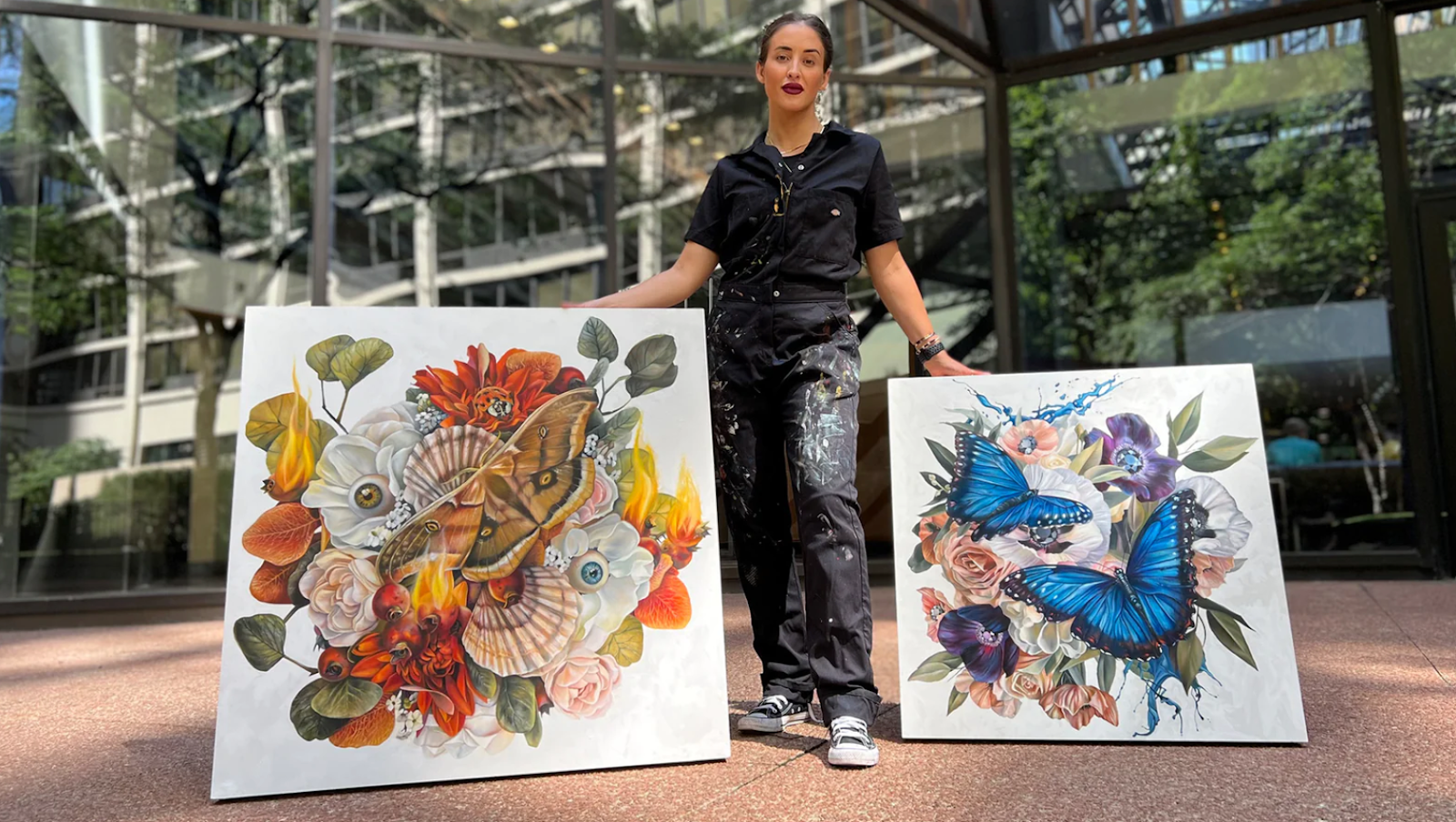 Artist Samantha DeCarlo with two of her paintings showing flowers and butterflies