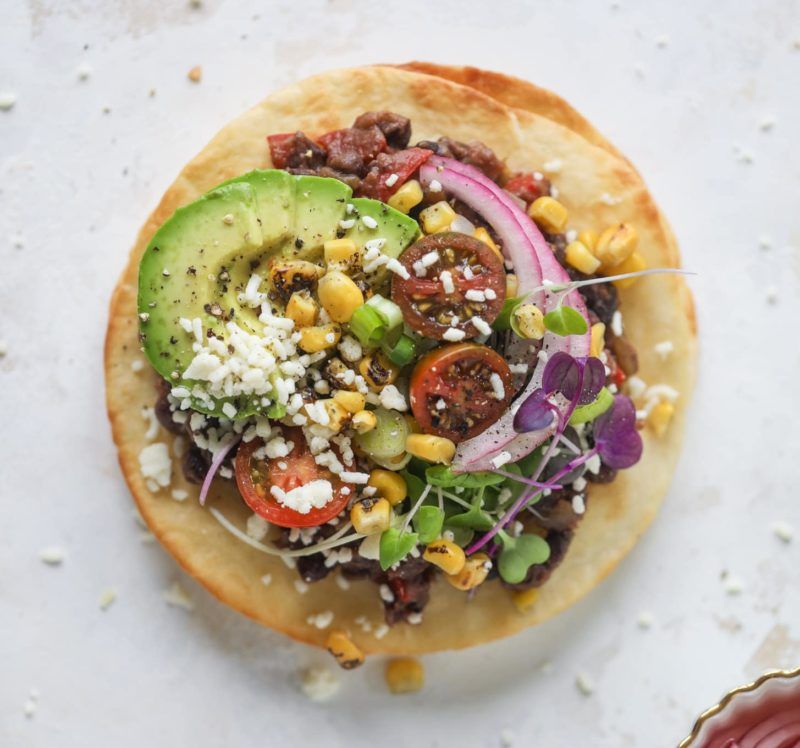 A tortilla with avocado tomatoes and corn on it