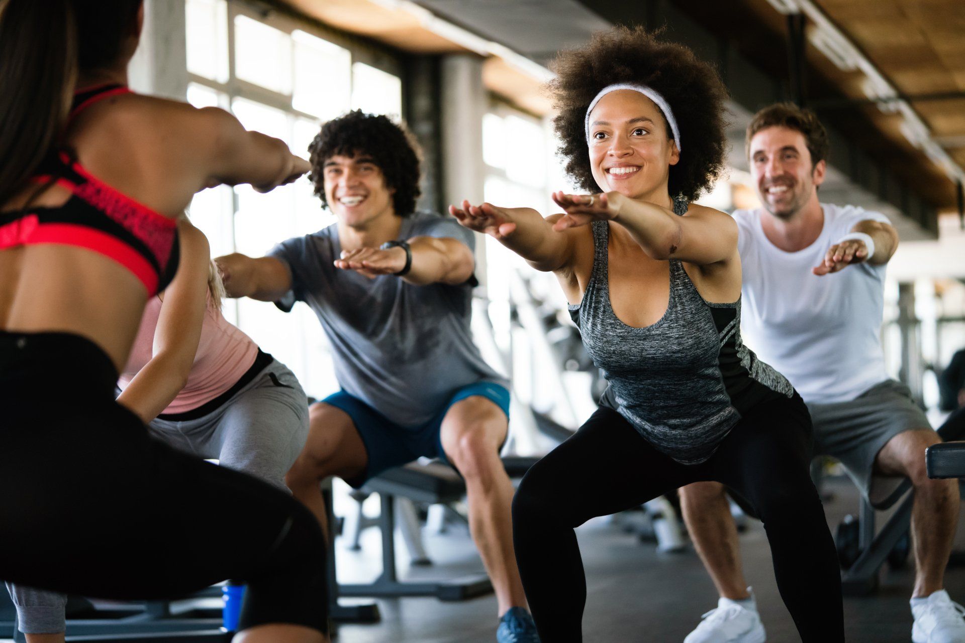 A group of people are doing squats in a gym.