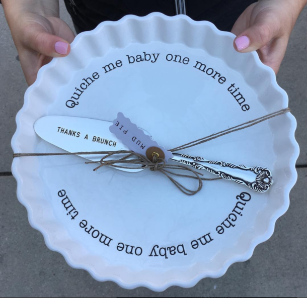 A person is holding a plate that says quiche me baby one more time