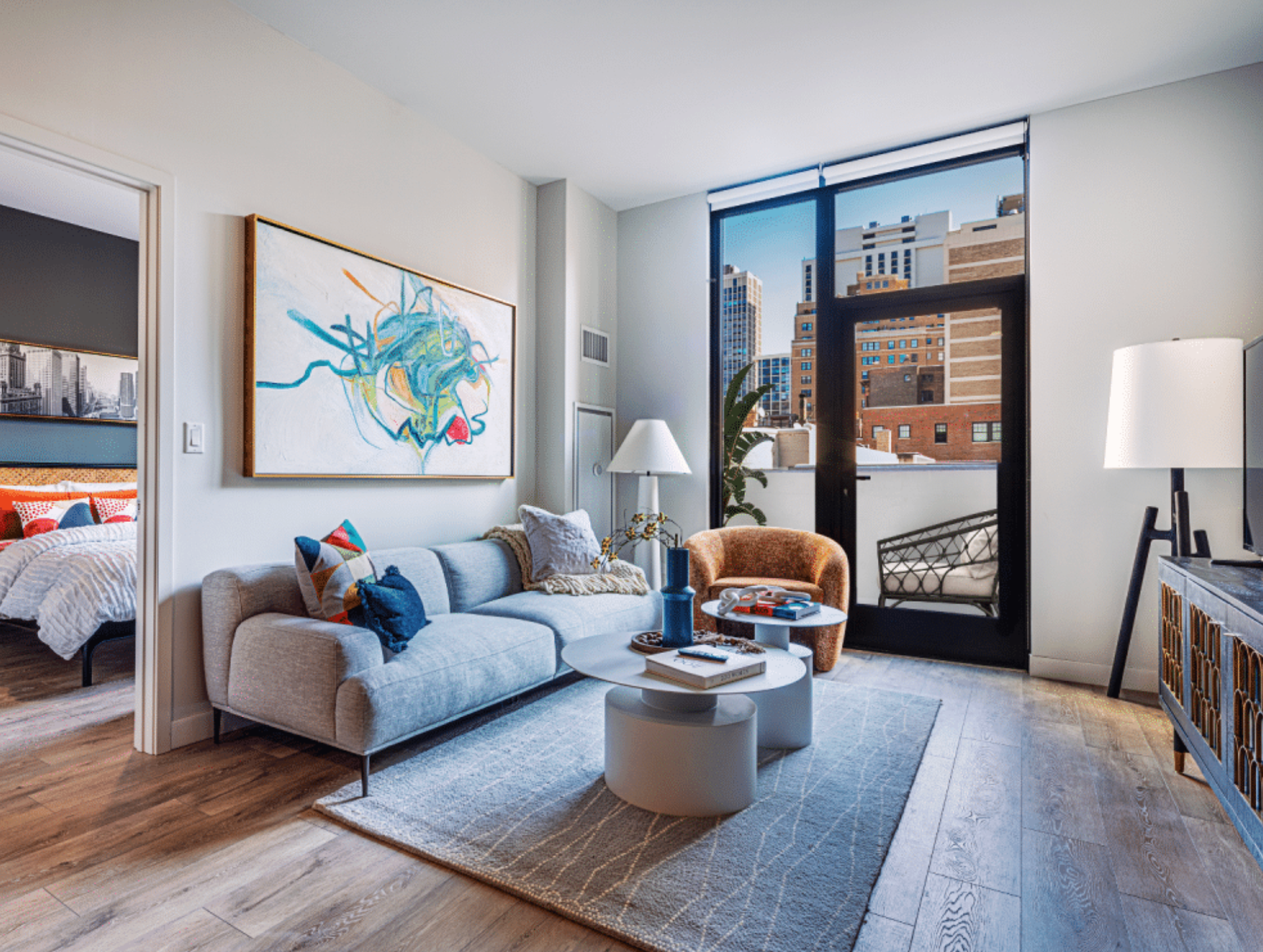 Modern living room with gray sofa, blue accents, and large city-view windows
