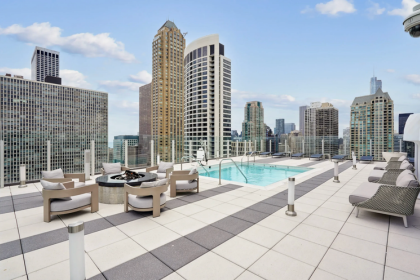 Rooftop pool lounge with beige seating and city skyline under a blue sky