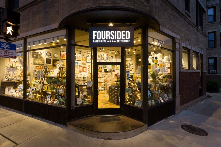 Foursided gift and framing shop exterior at twilight, featuring a lit storefront, display windows, and brick architecture.