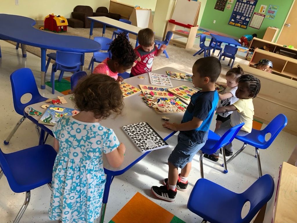 Children seated around tables doing an art activity in a colorful classroom