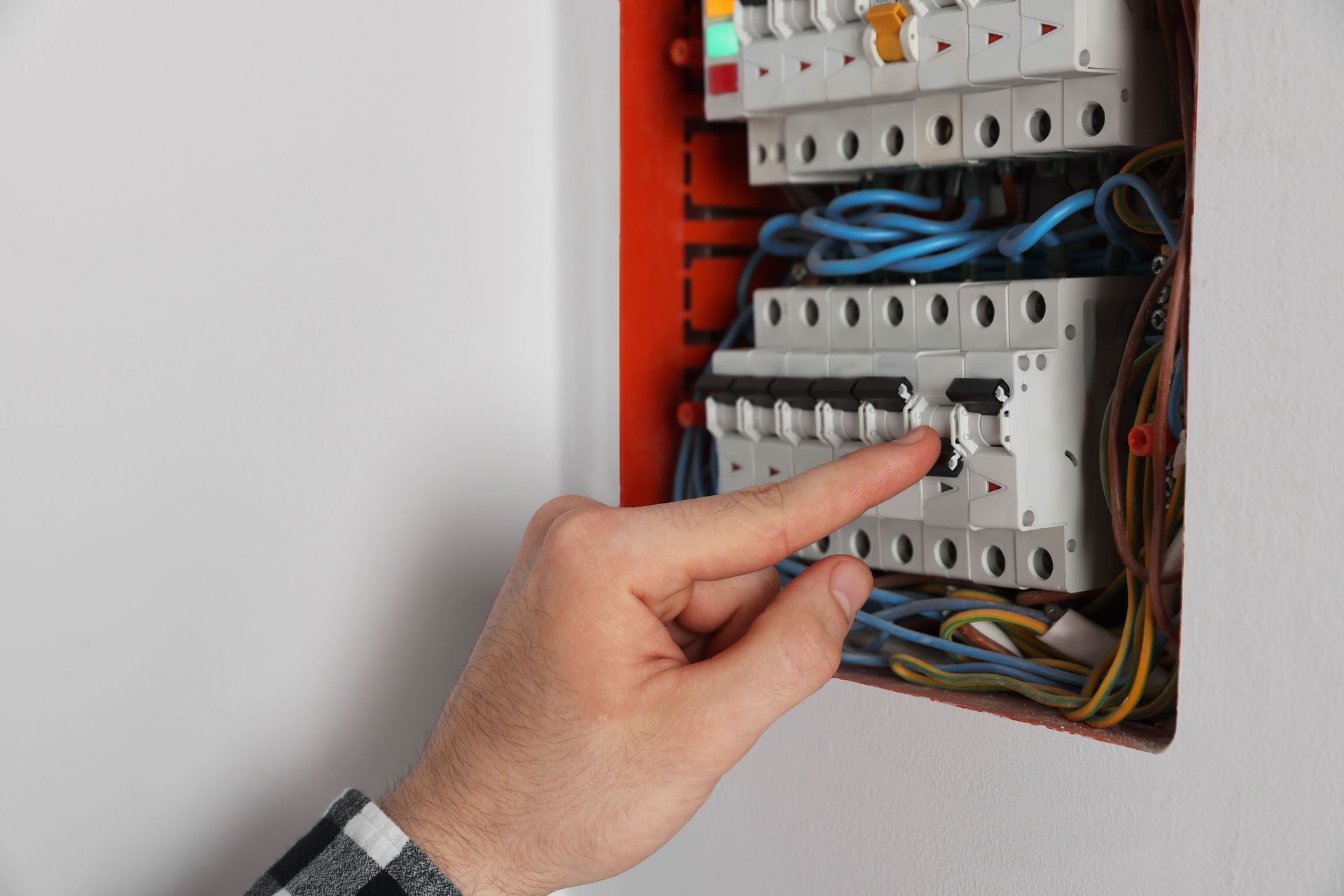 Hand adjusting breaker in an electrical panel with exposed wiring