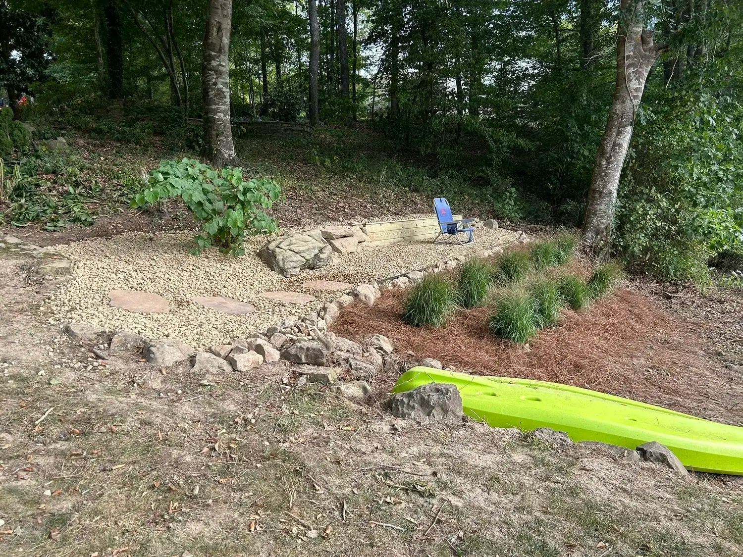A stone path made of large, irregular flagstones set in crushed blue-gray gravel, winding through a wooded garden.