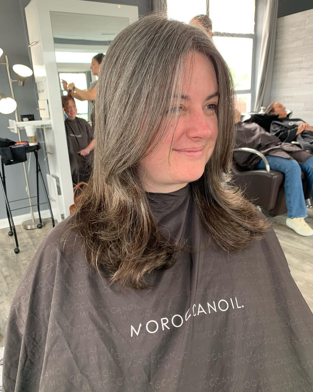 a woman getting her hair cut with a moroccanoil cape