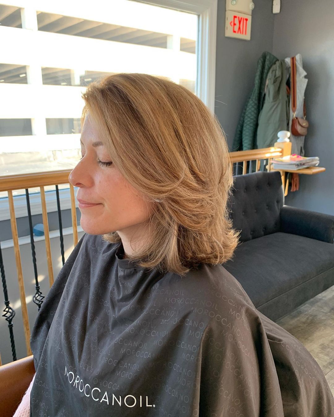 a woman wearing a moroccanoil cape sits on a couch