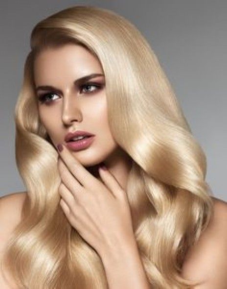 A woman with long blonde hair is covering her face with her hand.