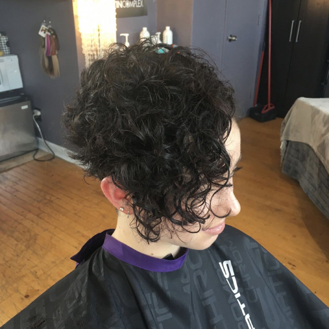 A woman with curly hair is wearing a black cape that says scissors