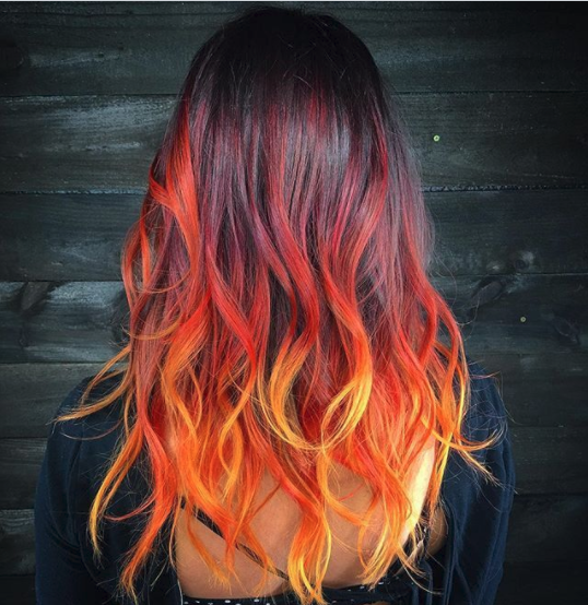 a woman with red and orange hair is wearing a black shirt