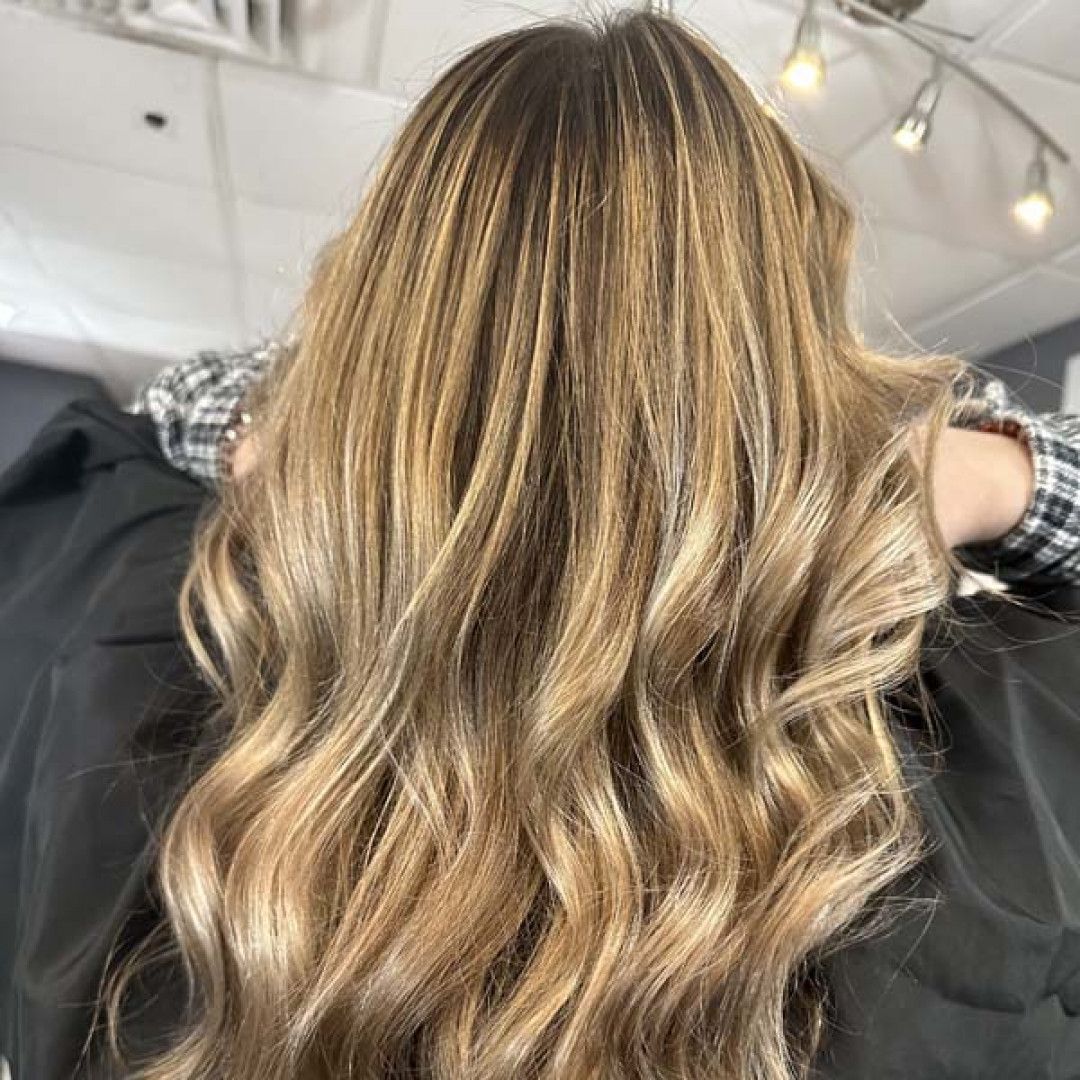 A woman with long blonde hair is sitting in a chair in a salon.