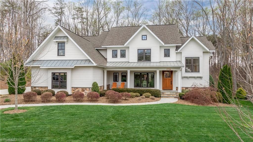 Large white two-story suburban house with gabled roof, front porch, and green lawn