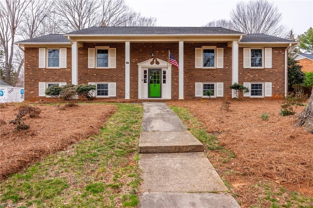 Brick house with green front door, central walkway, and brown winter landscaping