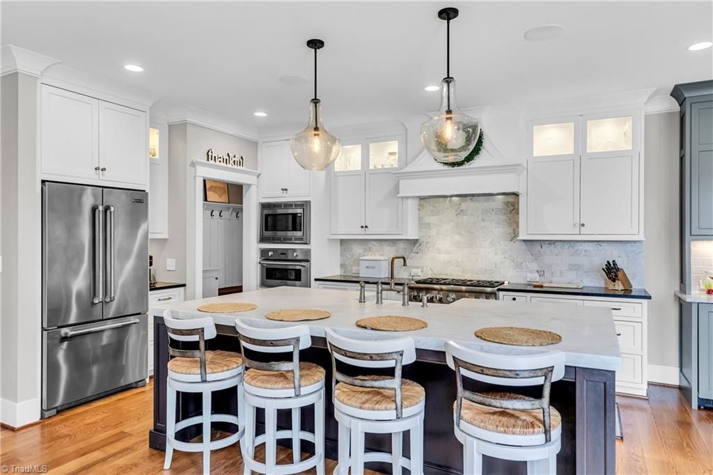 Bright white kitchen with island seating, stainless steel appliances, and pendant lights