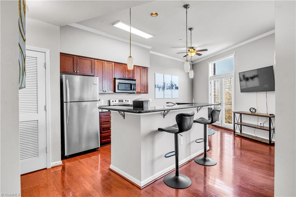 A kitchen with a stainless steel refrigerator , microwave , and bar stools.