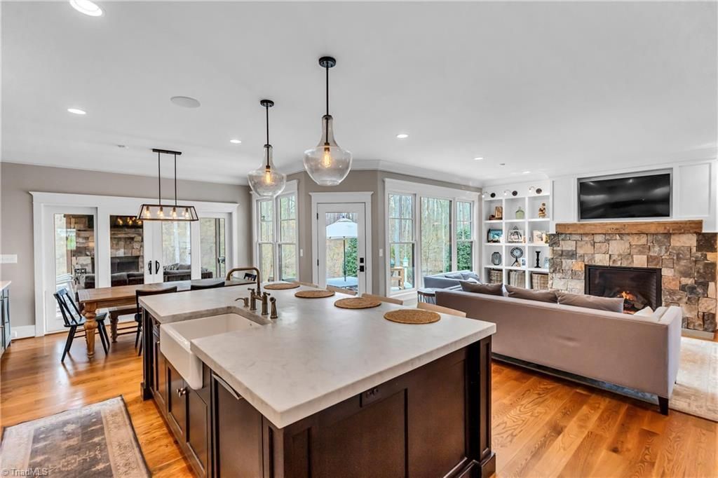 Open-concept kitchen and living room with island, pendant lights, gray sofa, and fireplace