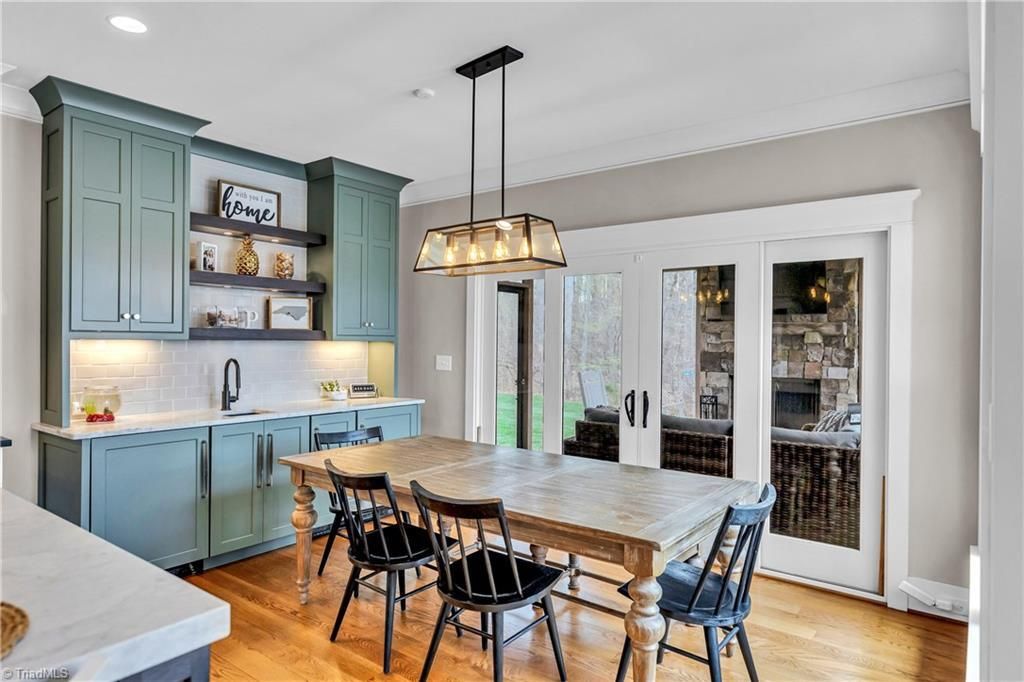 Bright kitchen dining room with blue cabinets, wooden table, black chairs, and glass doors to the outside