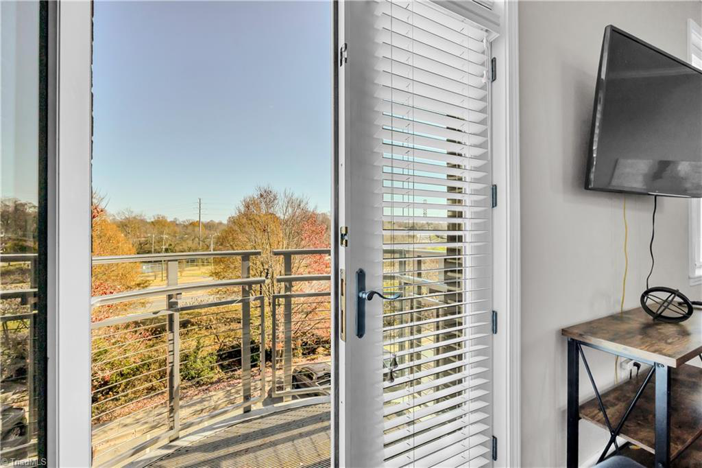 A room with a balcony and a flat screen tv on the wall.