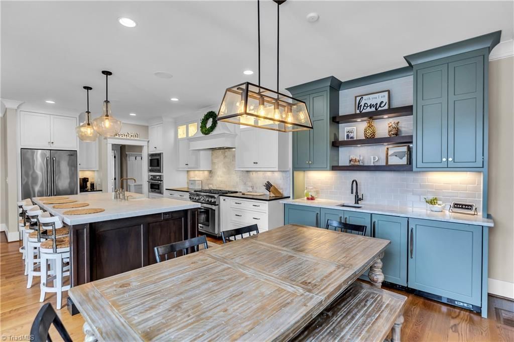 Bright modern kitchen with blue cabinets, large island, pendant lights, and barstools