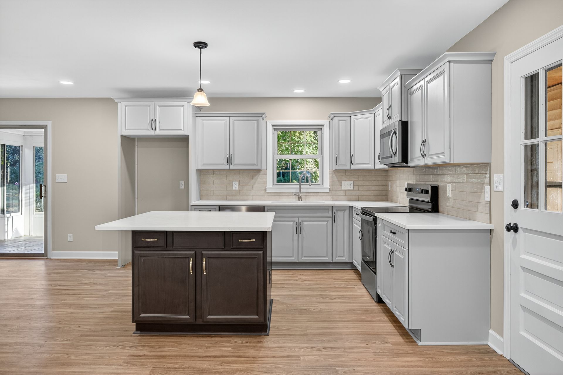 Bright modern kitchen with white cabinets, central island, gray counters, and wood floors