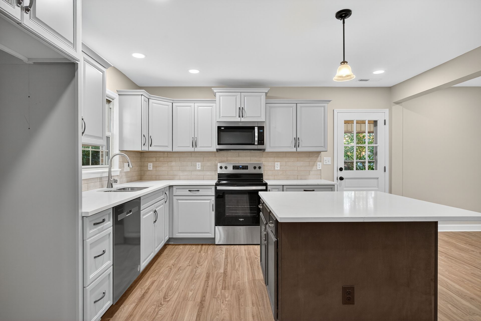 Bright modern kitchen with white cabinets, stainless appliances, and a large island.