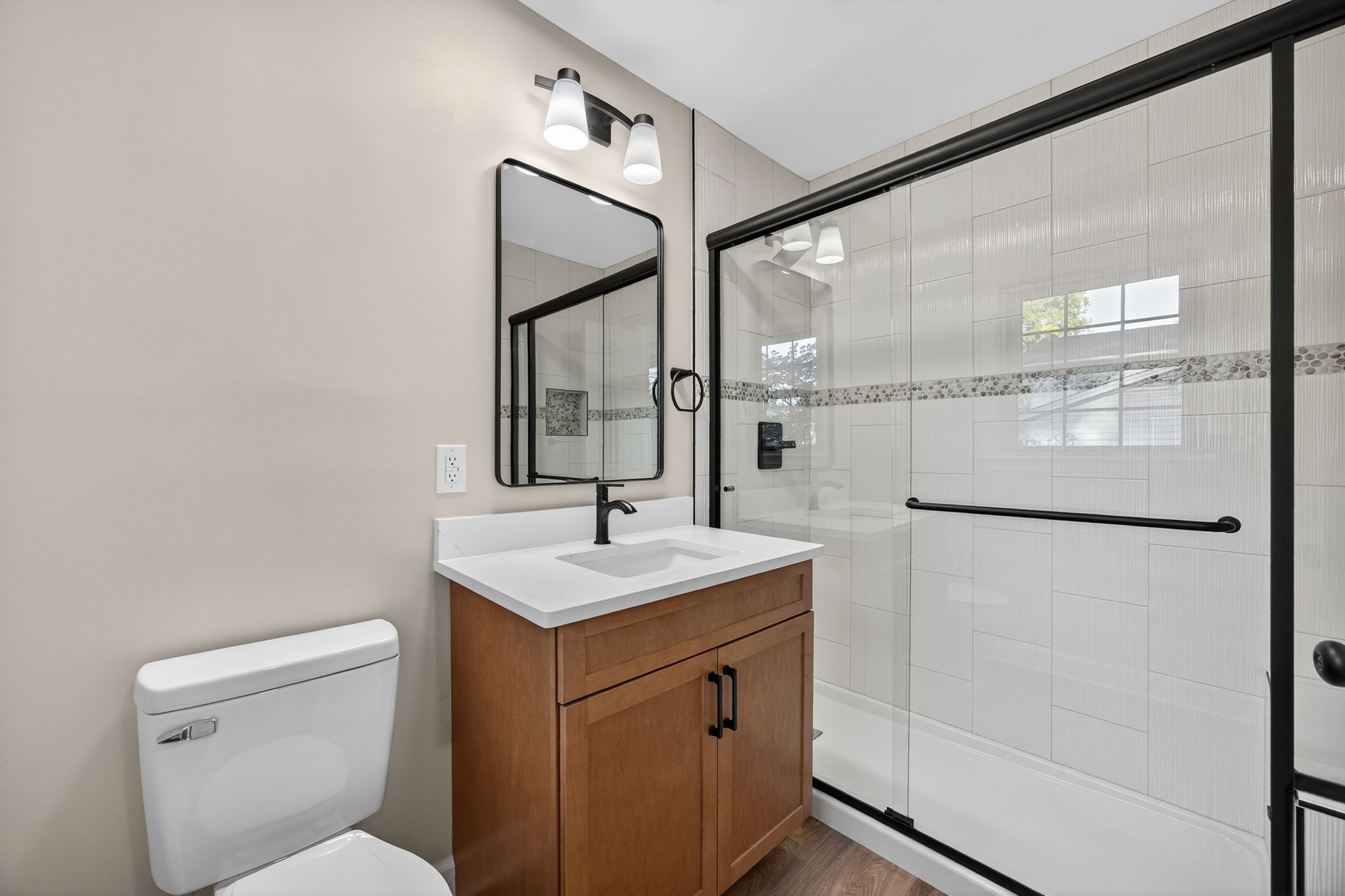 Modern bathroom with vanity, mirror, toilet, and glass-enclosed shower.