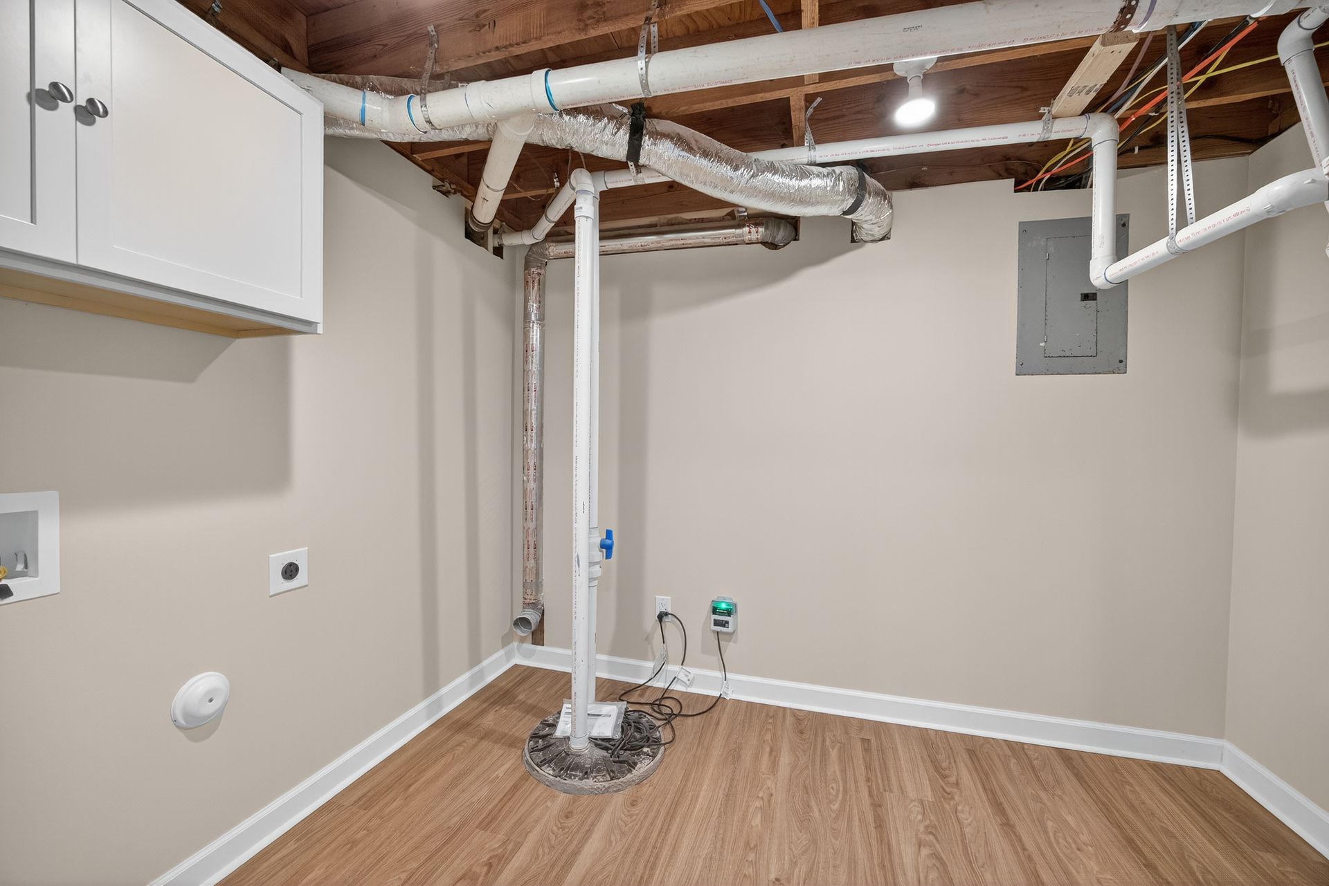 Unfinished basement utility room with exposed pipes, water heater, and wood-look flooring.