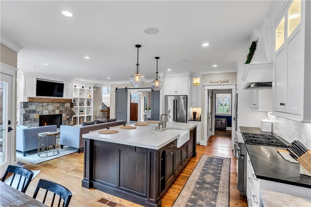 Bright modern kitchen with large island, white cabinets, pendant lights, and hardwood floors