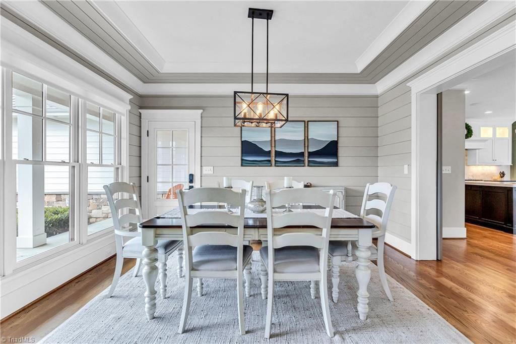 Bright dining room with white table, chairs, large windows, and a hanging pendant light