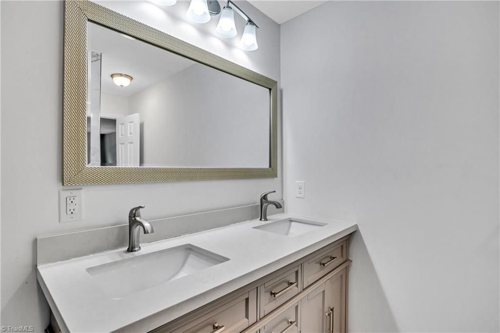 Modern bathroom vanity with double sinks, large mirror, and wall-mounted lights