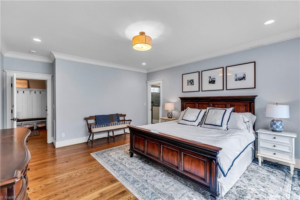 Bright bedroom with wooden bed, gray walls, hardwood floors, and framed art above the headboard