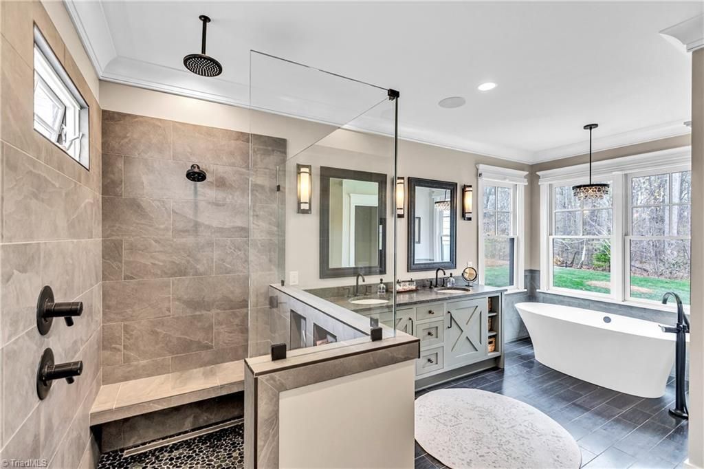 Modern bathroom with tiled shower, double vanity, soaking tub, and large windows