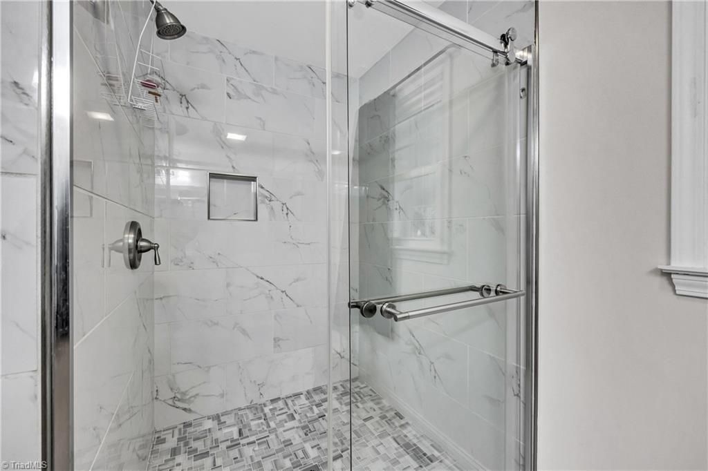 Modern bathroom shower with white marble tile and glass enclosure