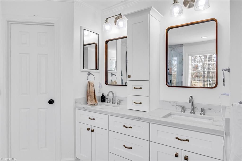Bright bathroom vanity with double mirrors, white cabinets, and chrome fixtures