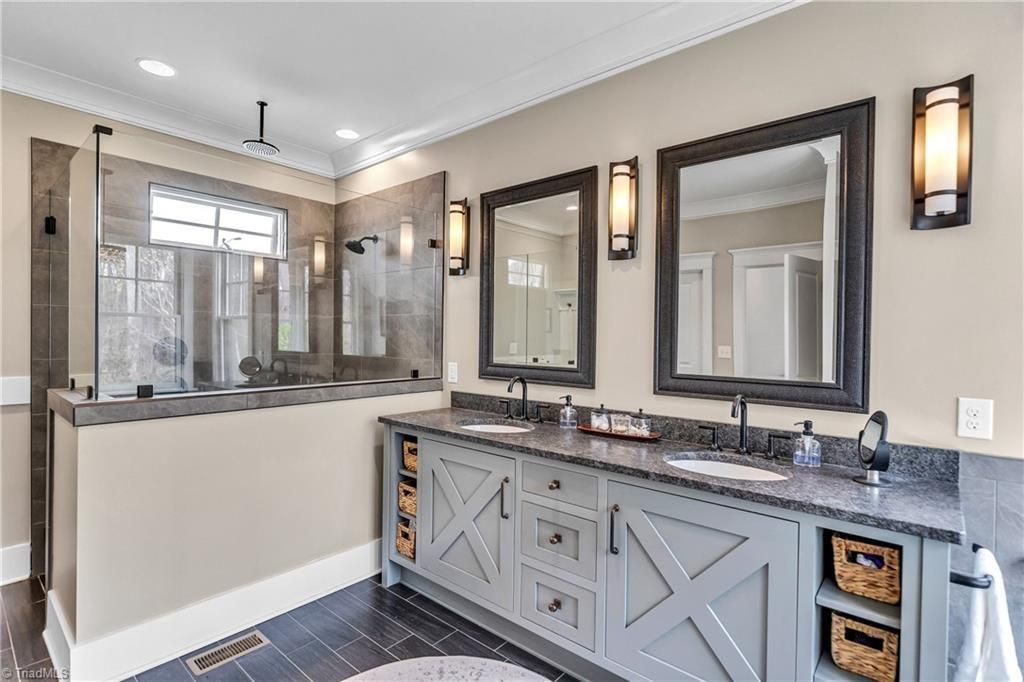 Elegant bathroom vanity with two framed mirrors, gray cabinets, and modern wall sconces