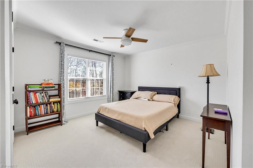 Bright bedroom with a bed, window, bookshelf, and lamp on a small table
