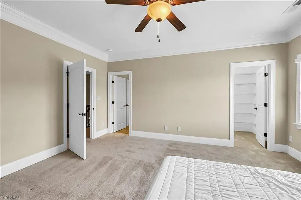 A bedroom with a bed and a ceiling fan.