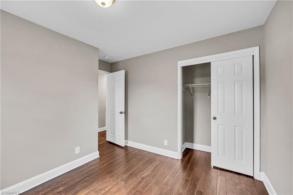 Empty bedroom with gray walls, wood floors, and two open closets