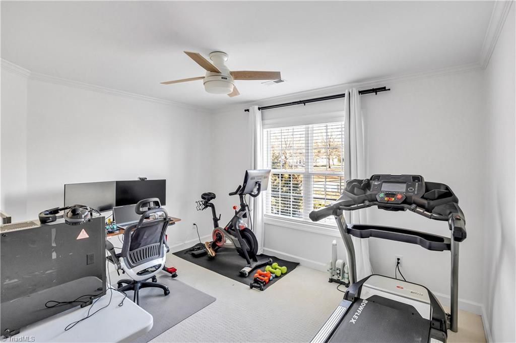 Small home gym with exercise bike, treadmill, and weight machine in a bright white room.