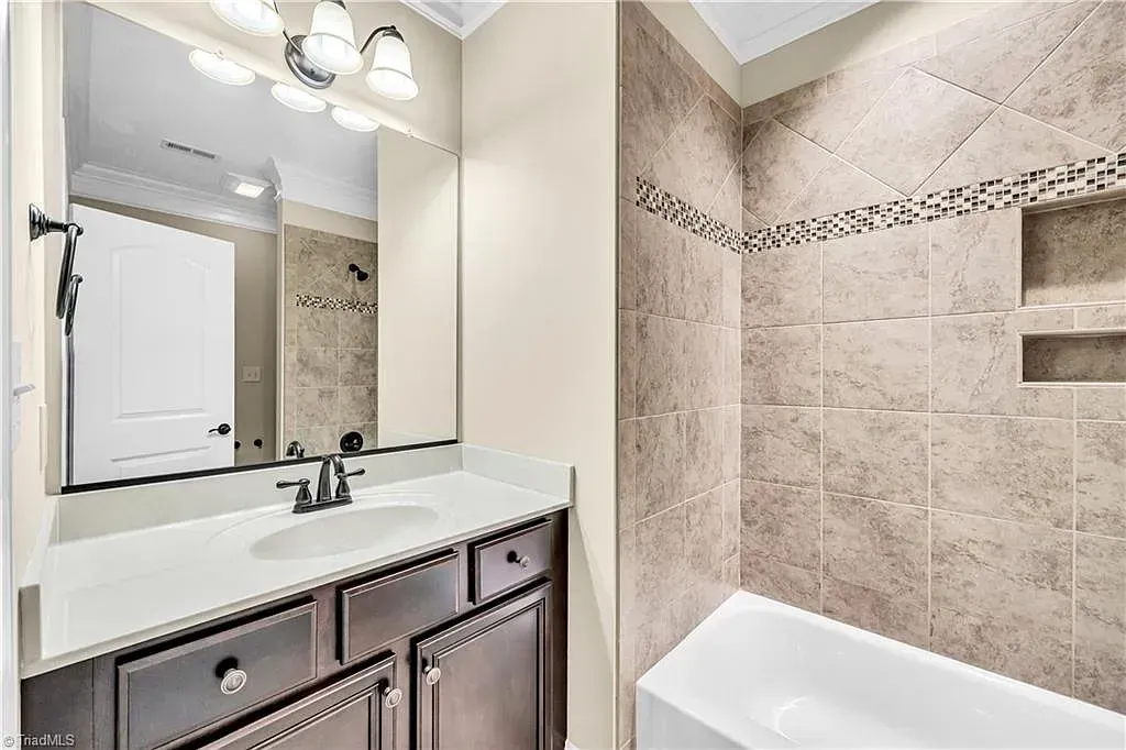 A bathroom with a sink , mirror and bathtub.