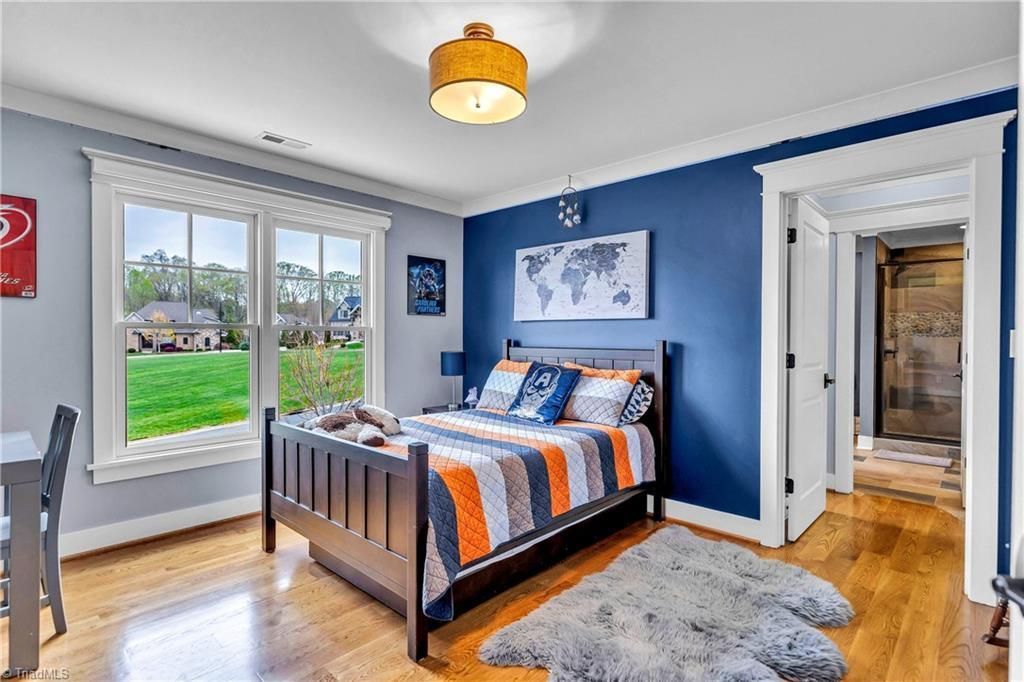 Blue bedroom with a gray bed, striped bedding, large window, and open door to a hallway