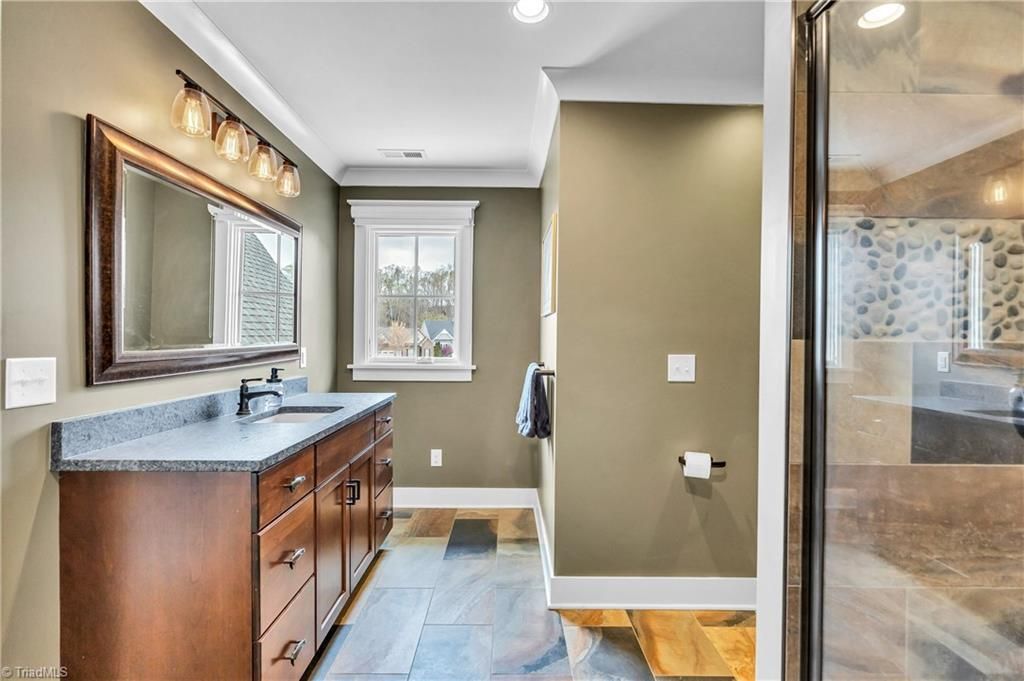 Modern bathroom with vanity, mirror, shower, and window in neutral tones
