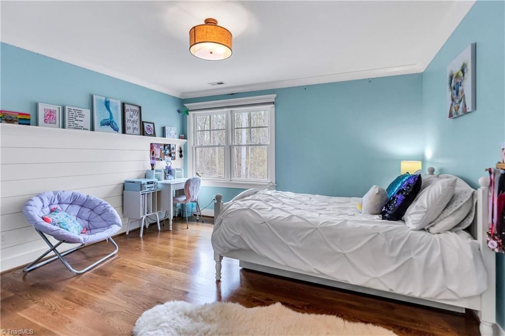 Bright blue bedroom with a daybed, desk, window, and hardwood floor￼