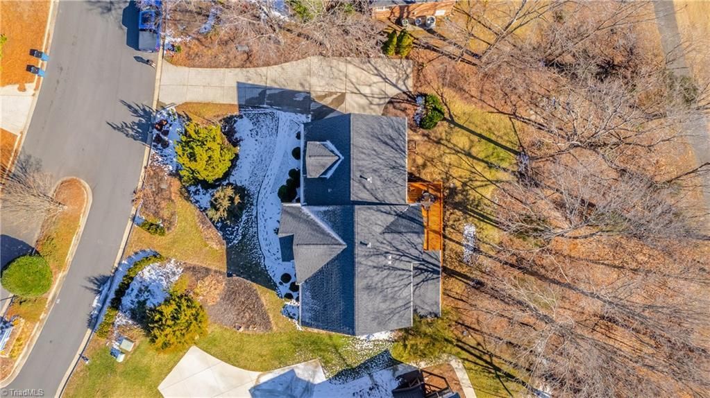 Aerial view of a gray-roofed house surrounded by trees and neighboring homes in fall.