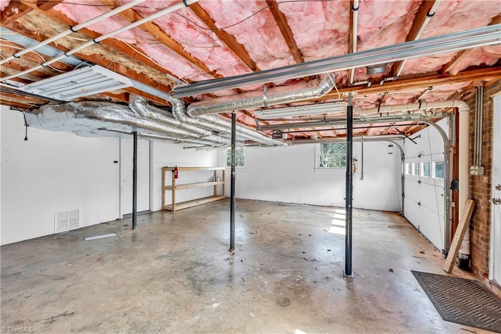 Unfinished basement with exposed insulation, concrete floor, and support columns