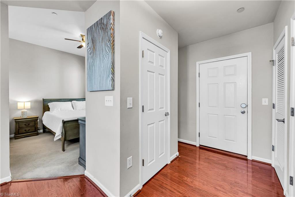 A hallway with hardwood floors and a bedroom in the background