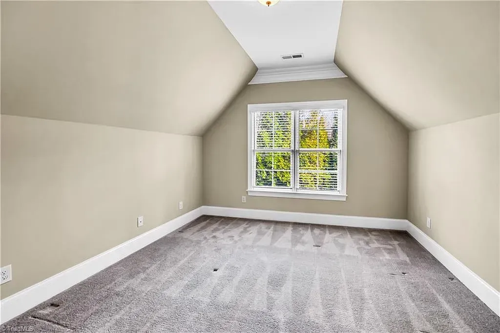 An empty room with a vaulted ceiling and a window
