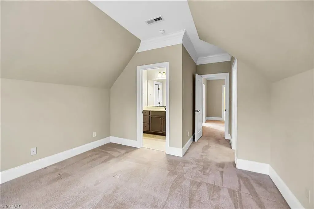 A bedroom with a vaulted ceiling and a carpeted floor.