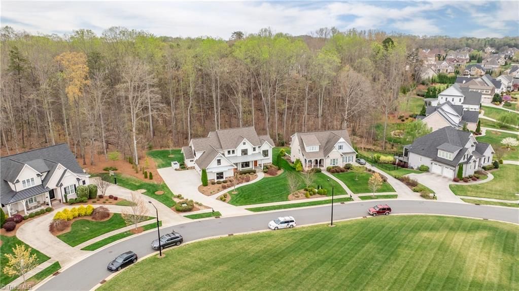 Aerial view of suburban houses along a curving road beside fields and woods